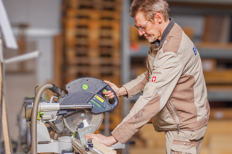 Schreiner sägt Holz für Bodenbeläge, Innentüren und Terrassen